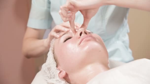Primer plano Spa masaje facial. Chica terapeuta de masaje profesional hace un masaje facial relajante a un cliente atractivo de un salón de spa — Vídeos de Stock