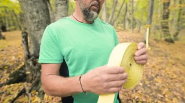 Sakallı bir adam, sonbahar ormanındaki denge kurma dersinden sonra ip toplar.