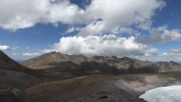 Timelapse de una parte de un glaciar y valle montañoso con montañas rocosas. Las nubes flotan en el cielo y sus sombras se mueven en las montañas . — Vídeo de stock