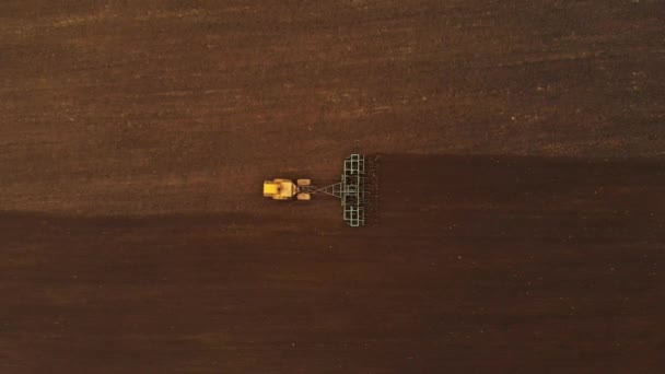 Flygfoto av en kraftfull gul traktor med stor ansträngning på kroken utför plöjning bearbetning för sådd vintergrödor med en disk kultivator på hösten — Stockvideo