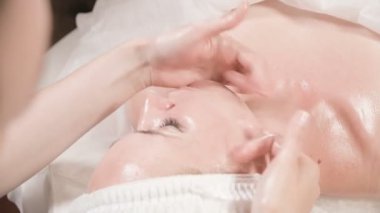 Kapalı Spa yüz masajı. Profesyonel masaj terapisti çekici bir spa salonu müşterisine yüz masajı yapıyor.