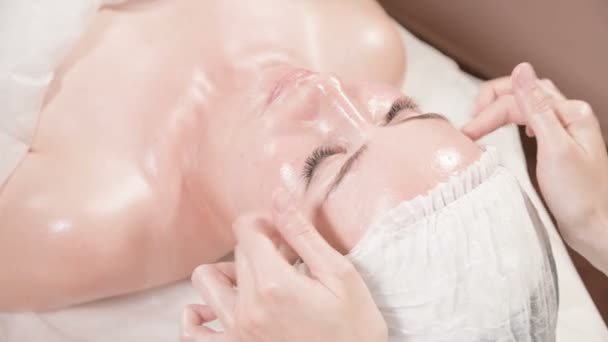 Close-up Spa gezichtsmassage. Meisje professionele massage therapeut doet een ontspannende gezichtsmassage naar een aantrekkelijke klant van een spa salon — Stockvideo