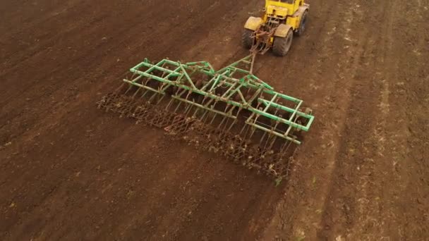 Vue aérienne d'un puissant tracteur jaune avec un grand effort sur le crochet effectuant le labour pour semer des cultures d'hiver avec un cultivateur à disque à l'automne 