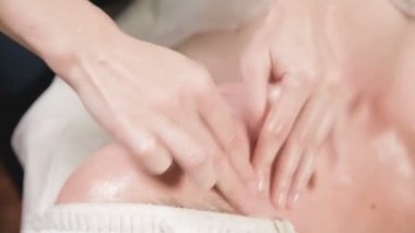 Kapalı Spa yüz masajı. Profesyonel masaj terapisti çekici bir spa salonu müşterisine yüz masajı yapıyor.
