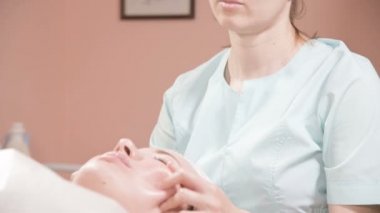 Kapalı Spa yüz masajı. Profesyonel masaj terapisti çekici bir spa salonu müşterisine yüz masajı yapıyor.