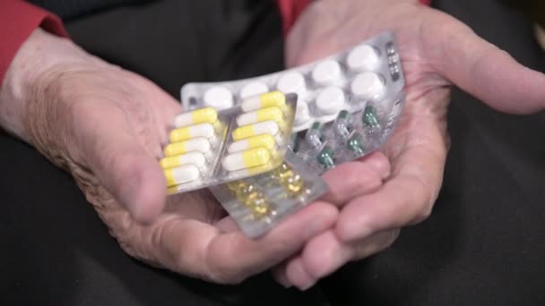 Zbliżenie tabletki na rękach starszej kobiety. Koncepcja wyboru leków w podeszłym wieku — Wideo stockowe