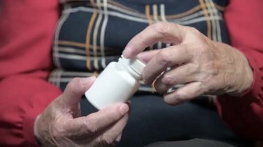 Omega-3 ilaç kapsülleri ve vitaminlerle beyaz bir kavanozu açan yaşlı bir kadının elleri. Sağlık konsepti hapları ve vitaminleri destekliyor