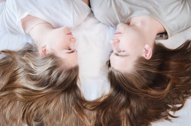 Çekici genç bir çiftin portresi bir kızla birlikte yatağa uzanıp birbirlerine bakıyorlar. Uzun saçlı, birbirine bağlı bir çift. Bir aile yaratma kavramı. Yukarıdan görüntüle