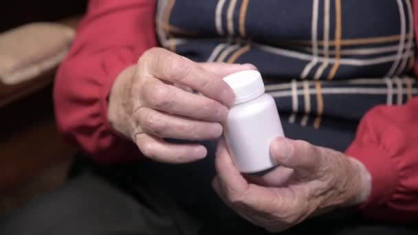 Руки пожилой женщины, открывающей белую банку с капсулами и витаминами омега-3. Концепция здоровья добавки таблетки и витамины — стоковое видео