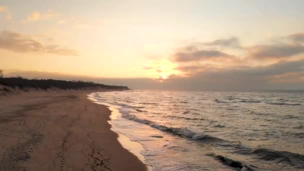 Imágenes aéreas de aviones no tripulados vuelo bajo sobre una playa desierta al atardecer. Orilla arenosa con olas onduladas y la puesta de sol sobre el horizonte. Paisaje marino — Vídeos de Stock