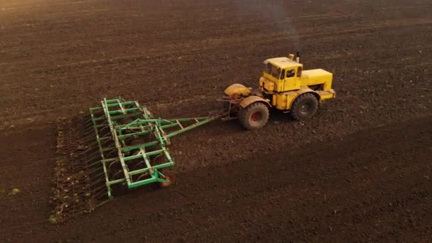 Vue aérienne d'un puissant tracteur jaune avec un grand effort sur le crochet effectuant le labour pour semer des cultures d'hiver avec un cultivateur à disque à l'automne 