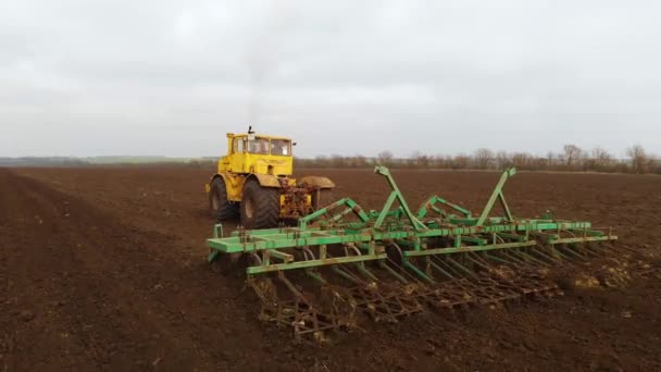 Vue aérienne d'un puissant tracteur jaune avec un grand effort sur le crochet effectuant le labour pour semer des cultures d'hiver avec un cultivateur à disque à l'automne 