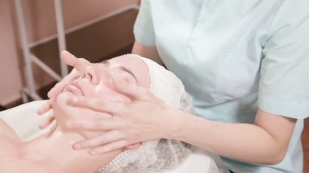 Girl beautician in a mask and gloves makes a salubrious facial massage to an attractive woman. New generation cosmetology massage — 비디오