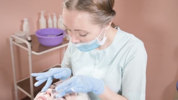 Girl beautician in a mask and gloves makes a salubrious facial massage to an attractive woman. New generation cosmetology massage — Αρχείο Βίντεο