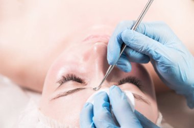 Güzellik salonunda sivilceler ve sivilceler için çelik bir aletle deriyi temizlemek için profesyonel bir işlem. Güzellik salonunda siyah başlık çıkarıcı ile bir kadının yüzünü derin bir temizleme..