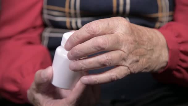 Χέρια μιας ηλικιωμένης γυναίκας που ανοίγει ένα λευκό βάζο με κάψουλες φαρμάκων ωμέγα-3 και βιταμίνες. Υγεία έννοια συμπληρώματα χάπια και βιταμίνες — Αρχείο Βίντεο