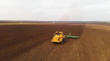 Tahıl ekmeden önce tarla süren sarı bir traktörün havadan görünüşü. Toprağı toprağa tohum ekmeye hazırlama kavramı. Çiftlik