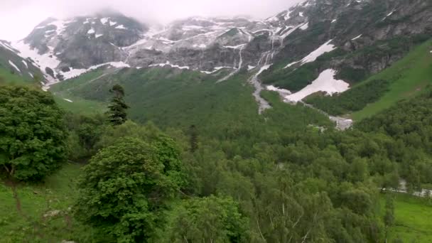 Yazın başında erimemiş yerlerin olduğu yüksek dağ şelalelerine doğru alçak uçuşlar. Turizm ve seyahat konsepti. Kuzey Kafkasya dağlarında şelaleler — Stok video