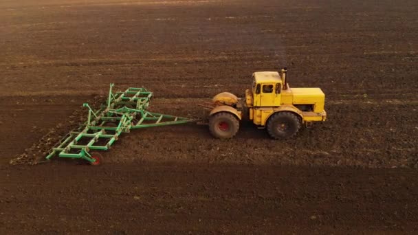 Vue aérienne d'un tracteur jaune avec une remorque labourant une terre labourant un champ cultivé avant de planter des céréales. Le concept de préparation de la terre pour planter des graines dans le sol. Exploitation agricole 