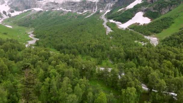 Vista aerea volo basso sopra la foresta a cascate di alta montagna con luoghi non sciolta neve all'inizio dell'estate. Turismo e concetto di viaggio. Cascate nelle montagne del Caucaso settentrionale — Video Stock