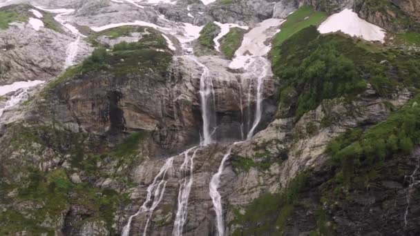 空中俯瞰无人机拍摄到几片瀑布从陡峭的岩石上滑落下来，这些岩石被茂密的青翠而不是融化的雪环绕着。 北高加索地区自然保护区的概念 — 图库视频影像
