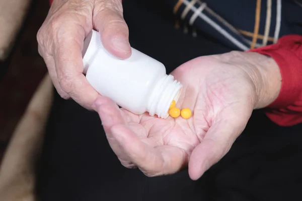 Hands of an old woman holding a white jar with omega-3 medicine capsules and vitamins. Health concept supplements pills and vitamins — Stock Photo, Image