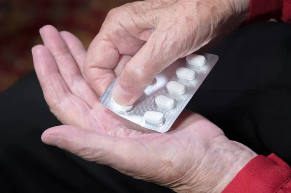 Hands of an old woman close-up. The old woman unpacks the tablets before use Stock Picture