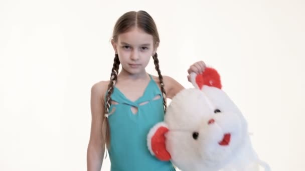 Девушка с косичками держит оторванную голову игрушечного медведя на белом фоне. Крупный план — стоковое видео