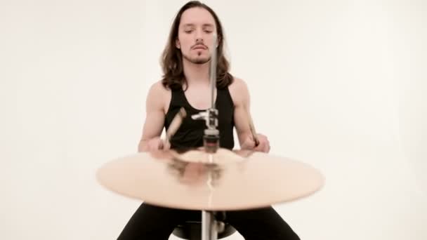Fešák v černém aktivně hraje na bicí soupravu na bílém pozadí. Closeup — Stock video
