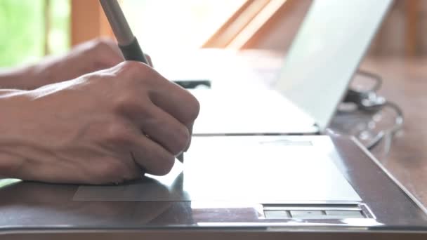 Крупный план мужчины-дизайнера рисует на своем ноутбуке с помощью. графический планшет и перо стилус — стоковое видео