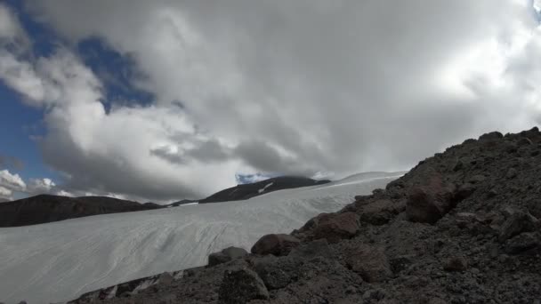 Timelapse de una parte de un glaciar y valle montañoso con montañas rocosas. Las nubes flotan en el cielo y sus sombras se mueven en las montañas . — Vídeos de Stock