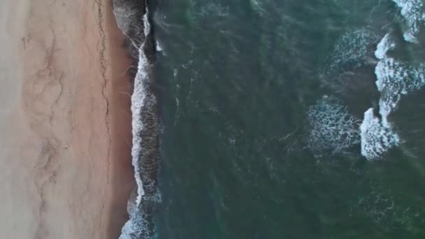 Vue aérienne d'une plage tropicale à l'heure bleue après le coucher du soleil montrant des images en soirée de vagues océaniques vertes mousseuses s'écrasant sur la côte. Vue de dessus sans personnes 