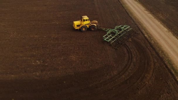 Vue aérienne d'un tracteur jaune avec une remorque labourant une terre labourant un champ cultivé avant de planter des céréales. Le concept de préparation de la terre pour planter des graines dans le sol. Exploitation agricole 