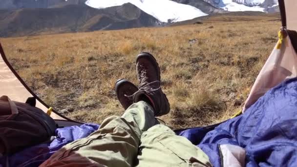 Tourist man takes video close-up of feet, beautiful view of mountains from tent. — ストック動画