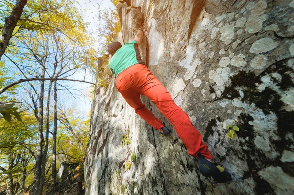 Ein frei gealterter männlicher Kletterer hängt an einer Felswand in einem Wald in den Bergen. Reifes Sportkonzept — Stockfoto