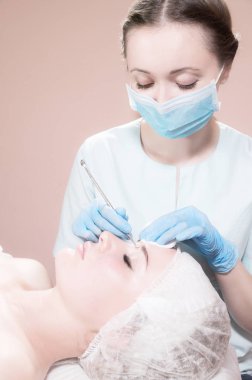 Güzellik salonunda sivilceler ve sivilceler için çelik bir aletle deriyi temizlemek için profesyonel bir işlem. Güzellik salonunda siyah başlık çıkarıcı ile bir kadının yüzünü derin bir temizleme..