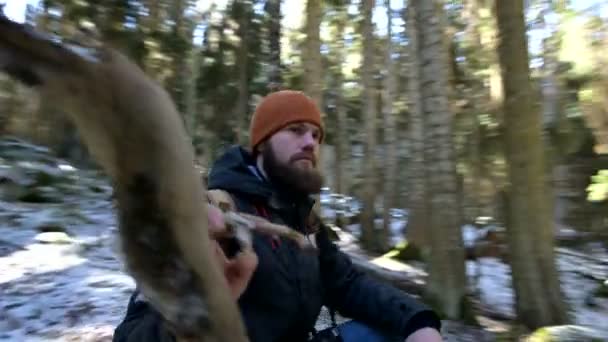 Jongeman met baard en rugzak in het winterbos. Camera pannen 360, close-up. — Stockvideo