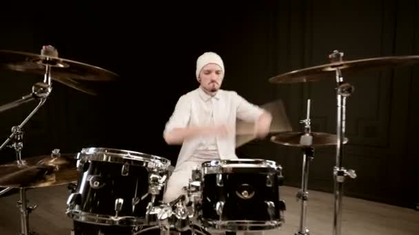 Schöner Kerl in weiß spielt aktiv auf Schlagzeug vor schwarzem Hintergrund. Nahaufnahme — Stockvideo
