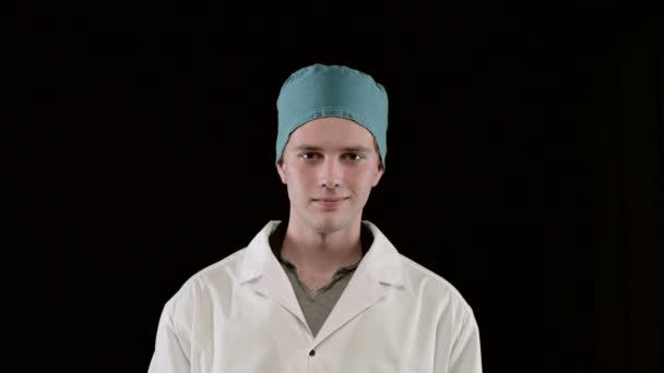 Молодой человек в медицинском пальто, показывает два шприца в руке. Черный фон, крупный план . — стоковое видео