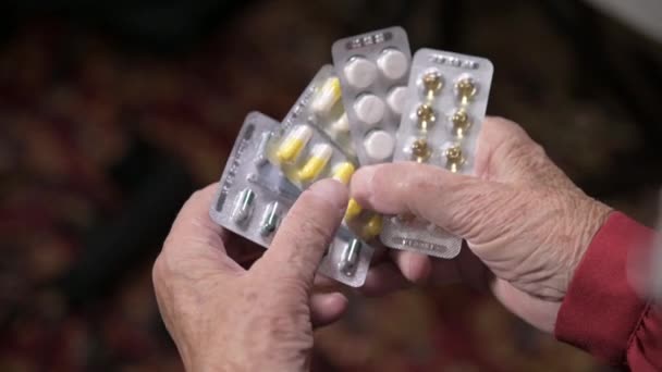 Κλείσιμο ενός δισκίου στα χέρια μιας γριάς γυναίκας. Η έννοια της επιλογής φαρμάκων στα γηρατειά — Αρχείο Βίντεο