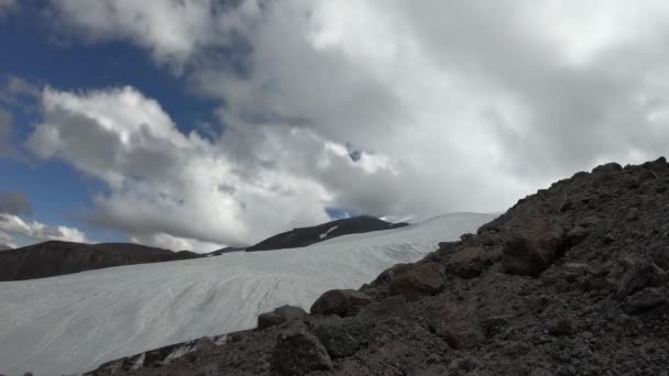 Timelapse d'une partie d'un glacier et d'une vallée de montagne avec des montagnes rocheuses. Les nuages flottent dans le ciel et leurs ombres se déplacent dans les montagnes . — Video