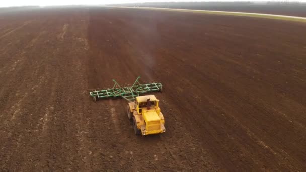 Luchtfoto van een krachtige gele trekker met grote inspanning op de haak uitvoeren ploegen tillage voor het zaaien van wintergewassen met een schijf cultivator in de herfst — Stockvideo