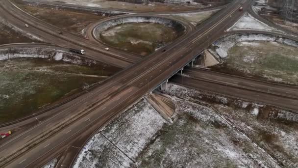 Luftaufnahmen von Autos und Lastwagen, die sich an einer winterlichen Kreuzung bewegen, sind eine große Straßenkreuzung. unbemannter Blick auf den Autoverkehr auf einer Autobahn in den Vororten im Winter. Kreisverkehr an der Kreuzung — Stockvideo