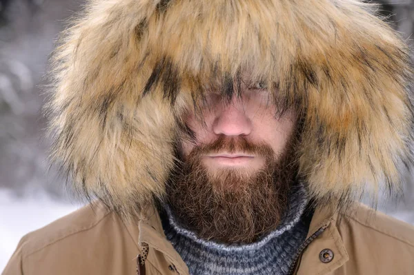 Um homem vestido com uma jaqueta casuais encapuzados outerwear popa de baixo do capô um retrato sério de uma pessoa na floresta de inverno. Tempo exterior — Fotografia de Stock