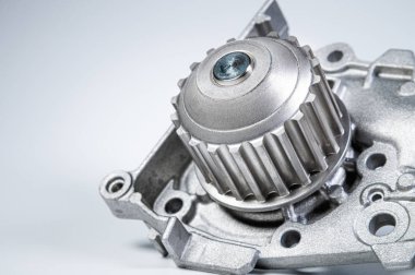 Gri arka planda bir su pompasının motorunu soğutmak için yeni metal otomobil pompası. Araba motoru için yeni yedek parça kavramı