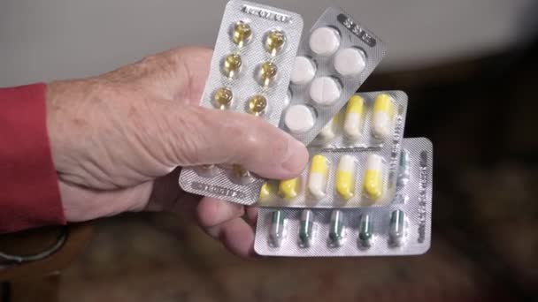 Primer plano de una tableta en las manos de una anciana. El concepto de elegir medicamentos en la vejez — Vídeo de stock