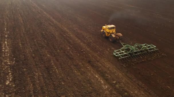 Vue aérienne d'un tracteur jaune avec une remorque labourant une terre labourant un champ cultivé avant de planter des céréales. Le concept de préparation de la terre pour planter des graines dans le sol. Exploitation agricole 