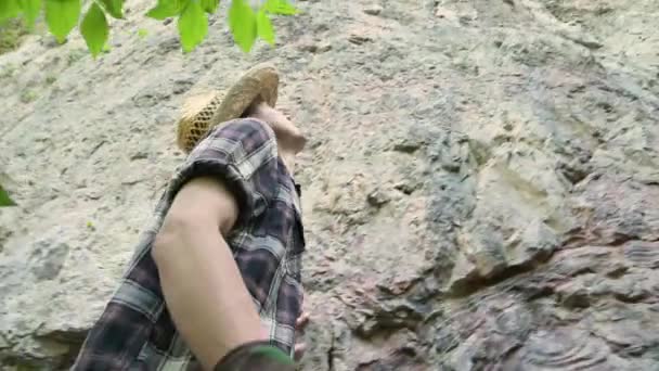 Ung man i hatt går barfota längs bergsvägen, tittar upp. Sommar. — Stockvideo