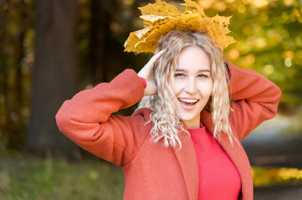 Retrato de menina loira branca atraente em casaco vermelho com um buquê de folhas amarelas caídas sorrindo na floresta de outono. O conceito de outono e outono feriados e fins de semana — Fotografia de Stock