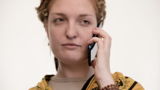 Etnisk kvinna som pratar i telefon, upprörd. Vit bakgrund. Närbild. — Stockvideo